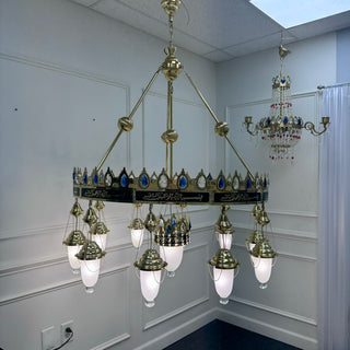 Large ornate chandelier hanging in a room with white walls and a ceiling light fixture.